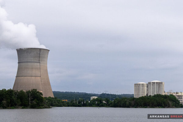 Arkansas Nuclear One's cooling tower releases steam across Lake Dardanelle, with the plant's reactor containment buildings visible to the right.