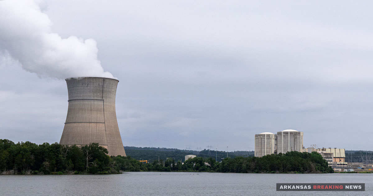 Arkansas Nuclear One's cooling tower releases steam across Lake Dardanelle, with the plant's reactor containment buildings visible to the right.