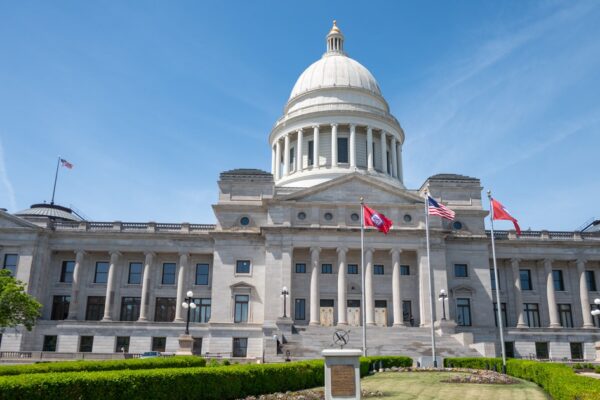 Front of the Arkansas State Capitol in Little Rock, with the dome and the U.S. and Arkansas flags on a clear day