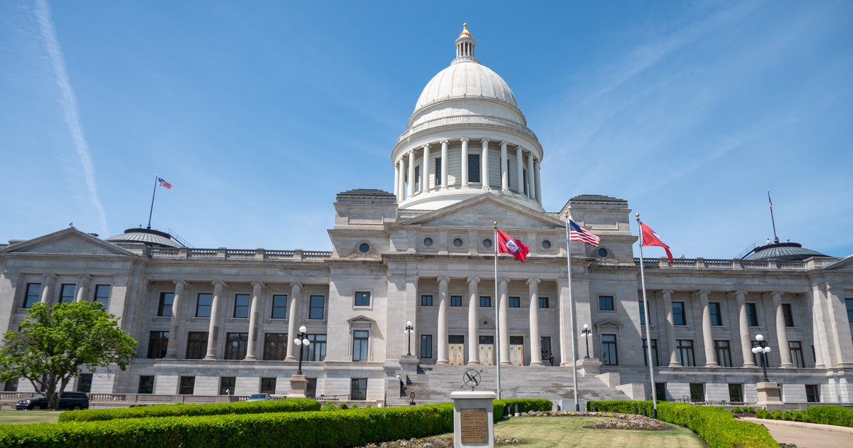 Front of the Arkansas State Capitol in Little Rock, with the dome and the U.S. and Arkansas flags on a clear day