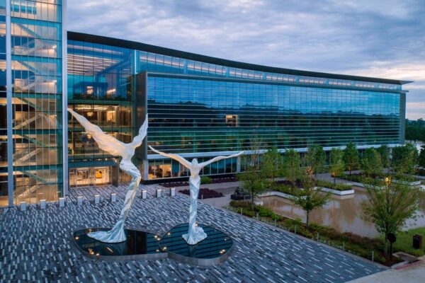 Bank OZK's glass headquarters building in Little Rock with two white winged sculptures in the front plaza