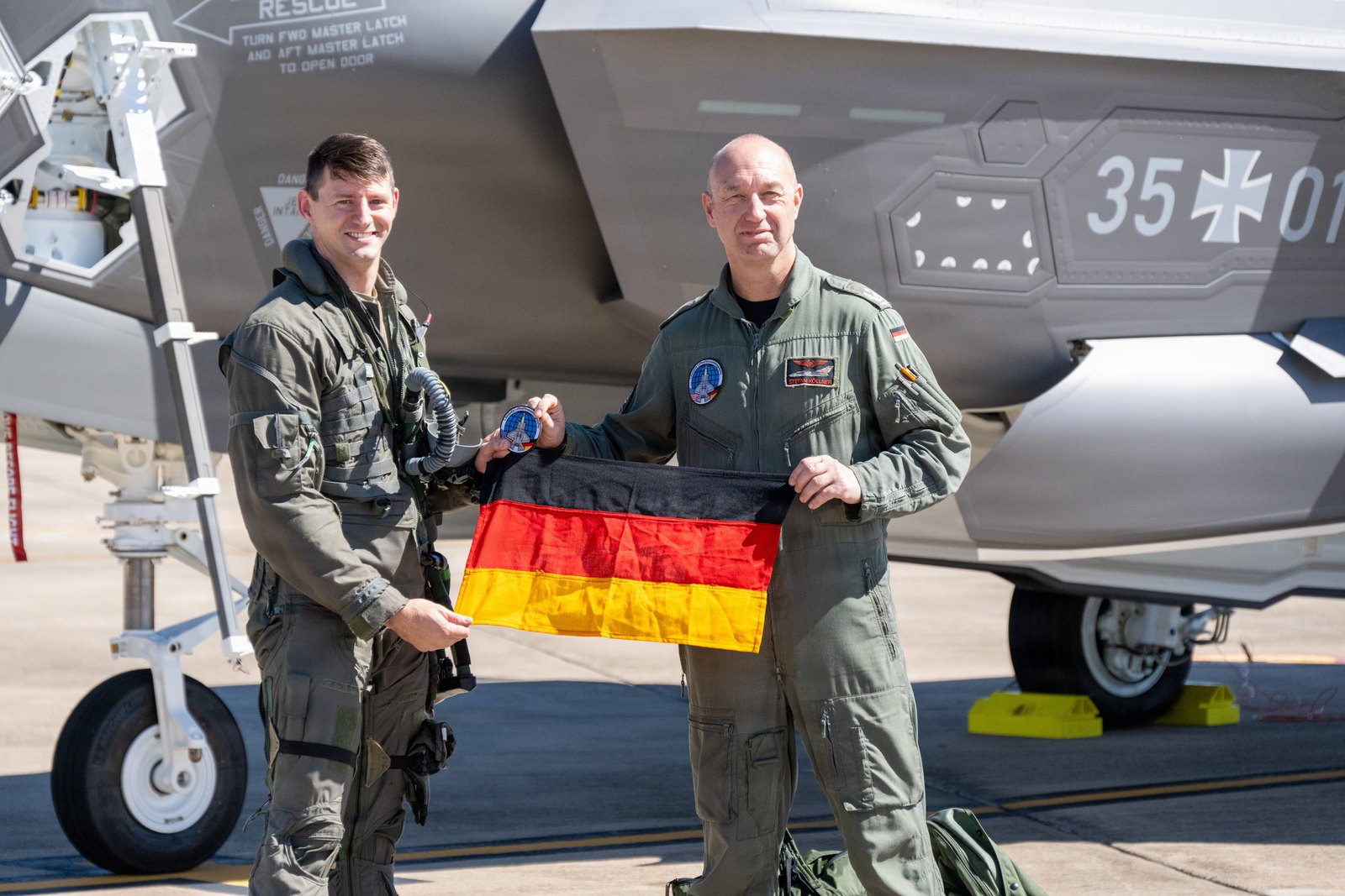 Maj. Eric Fesmire and German Air Force Lt. Col. Stefan Koellner hold a German flag beside the first German F-35, tail number 35+01, at Ebbing Air National Guard Base