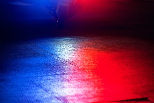 Red and blue police emergency lights reflected on pavement at night