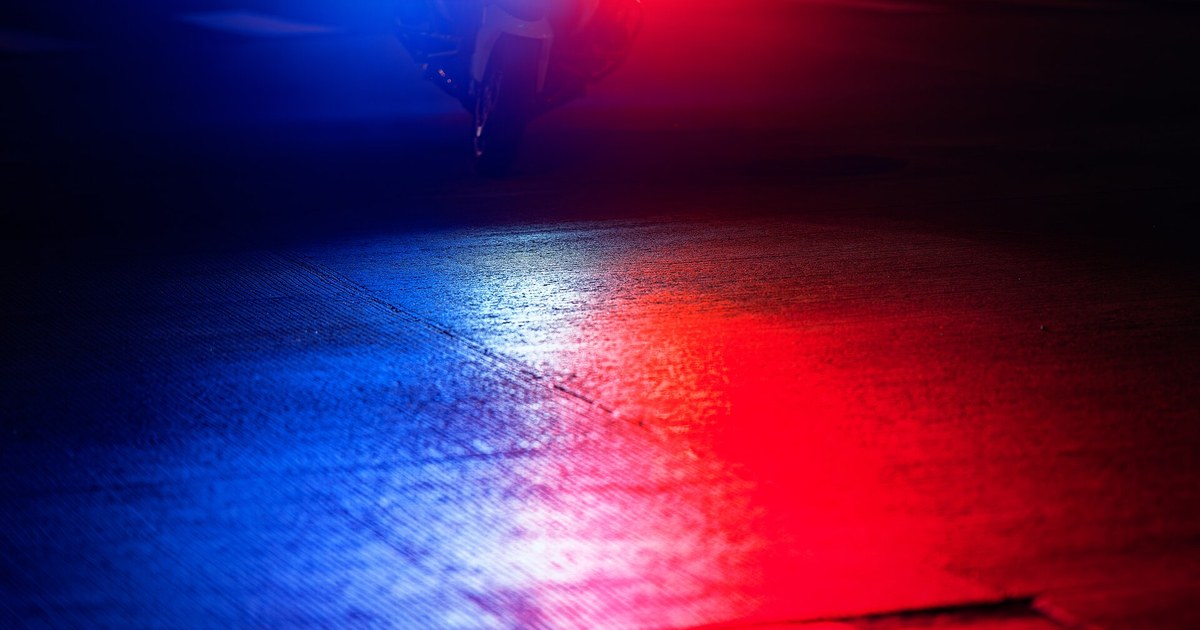 Red and blue police emergency lights reflected on pavement at night