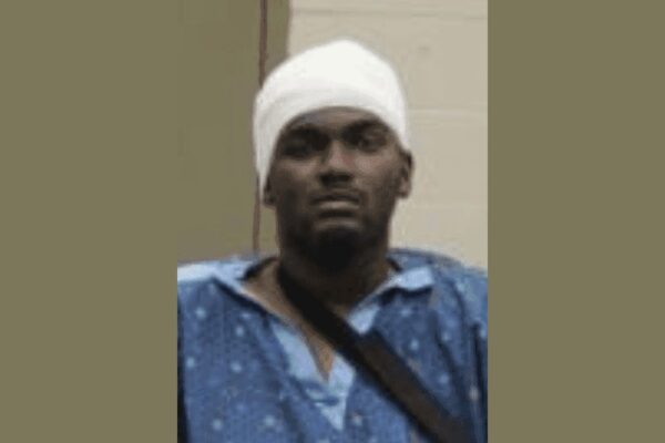Booking photo of Samuel Lamar Shelton wearing a hospital gown and a head bandage