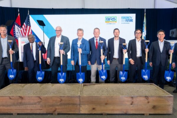 Nine men in suits hold blue ceremonial shovels behind a box of dirt at the U.S. Steel groundbreaking in Osceola